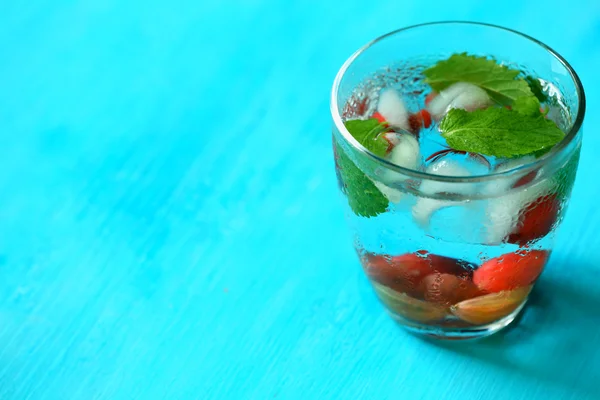 Szklanka zimnego orzeźwiającego napoju letniego z jagodami i kostkami lodu na stole — Zdjęcie stockowe