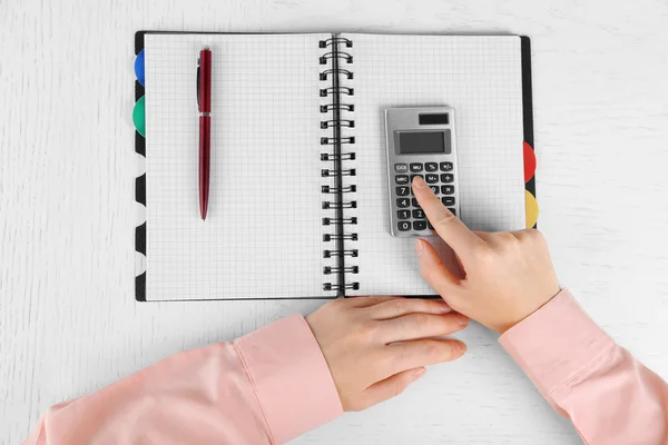 Manos trabajando en la oficina con cuaderno y calculadora, sobre mesa blanca —  Fotos de Stock