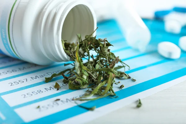 Láhev suchého lékařské marihuany a prášky s schránky na stole zblízka — Stock fotografie