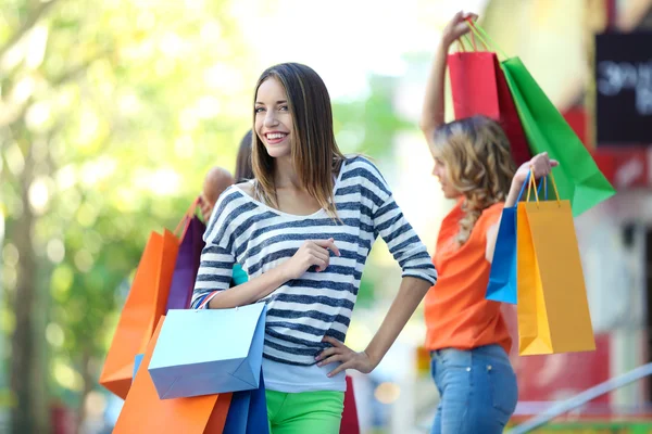 Beautiful young women with shopping bags on city street — Stock Photo, Image