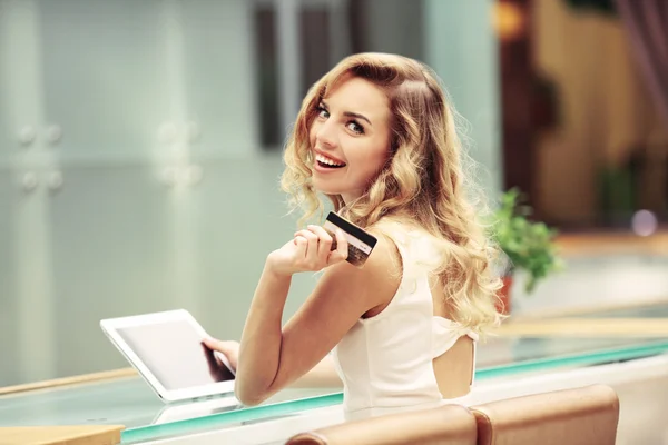Mulher bonita com tablet digital e cartão de crédito no café — Fotografia de Stock