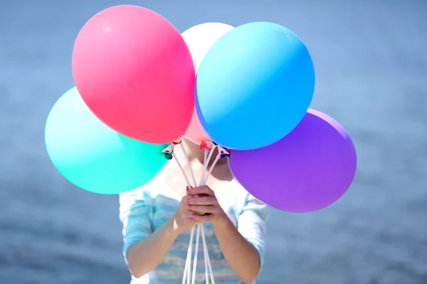 Flicka innehav ballonger nära ansikte — Stockfoto