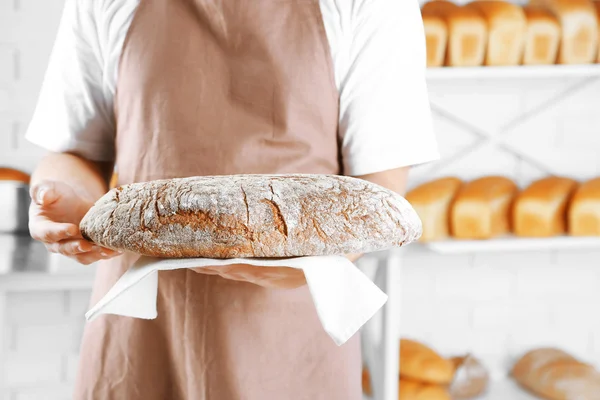 Пекарь держит свежеиспеченный хлеб — стоковое фото