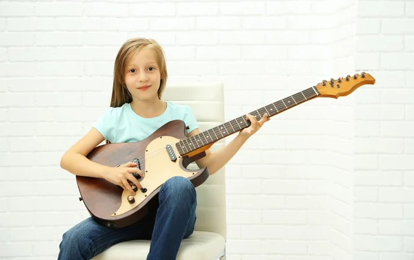 Niña tocando la guitarra sobre fondo claro — Foto de Stock