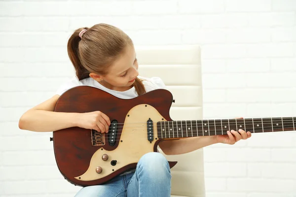 Little girl playing guitar on light background — Stock Photo, Image