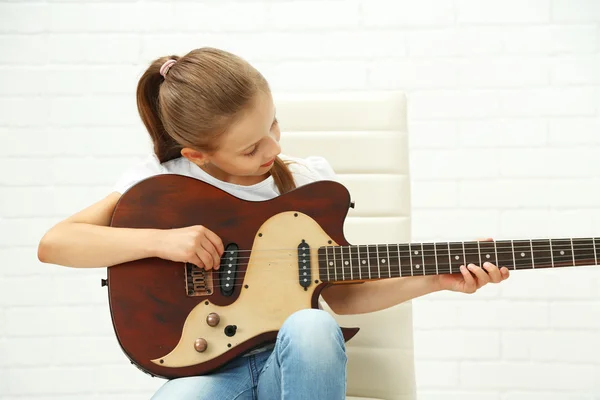 Niña tocando la guitarra sobre fondo claro —  Fotos de Stock