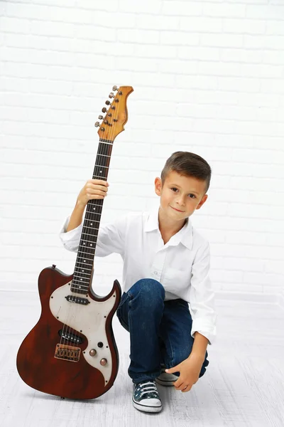 Malý chlapec s kytarou na světlé pozadí — Stock fotografie