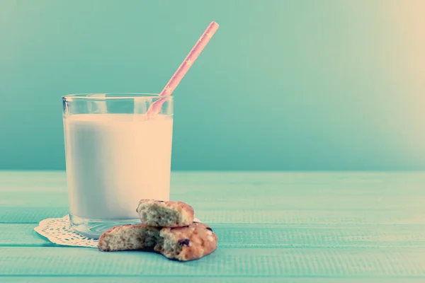 Galletas sabrosas y vaso de leche en la mesa sobre fondo turquesa — Foto de Stock