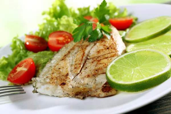 Prato de filé de peixe com salada e limão na chapa de perto — Fotografia de Stock