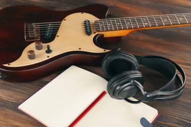 Elektro gitar ahşap masa üstünde defter ve kulaklık ile yakın çekim