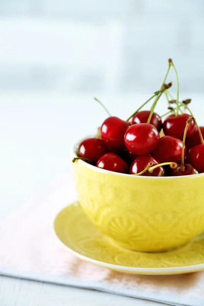 Třešně v hrnek na stole, na světlé pozadí — Stock fotografie