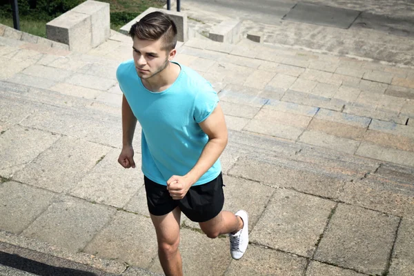 Young man jogging at stairs outdoors — Stock Photo, Image
