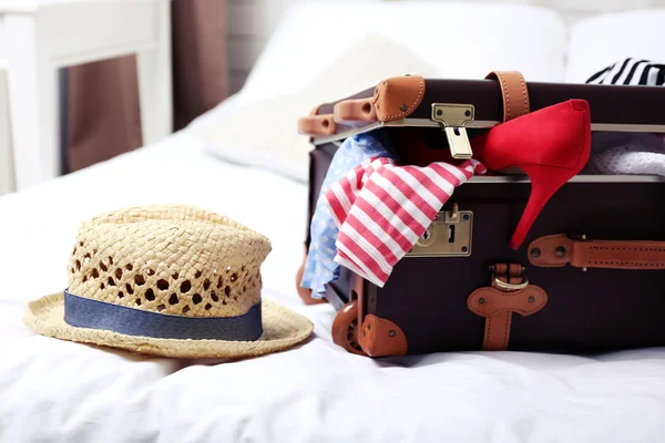 Suitcase with clothing on bed — Stock Photo, Image