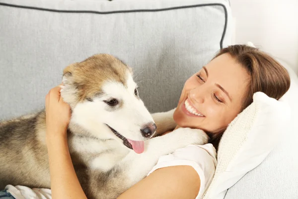 Kadın malamute köpeğiyle yalan — Stok fotoğraf