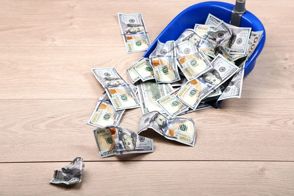 Dólares em colher de lixo no fundo do chão de madeira — Fotografia de Stock