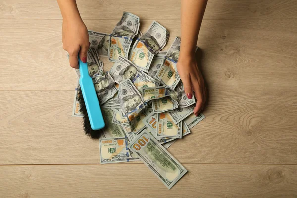 Woman broom sweeps dollars in heap — Stock Photo, Image