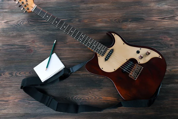 Elektrická kytara s Poznámkový blok na dřevěný stůl zblízka — Stock fotografie