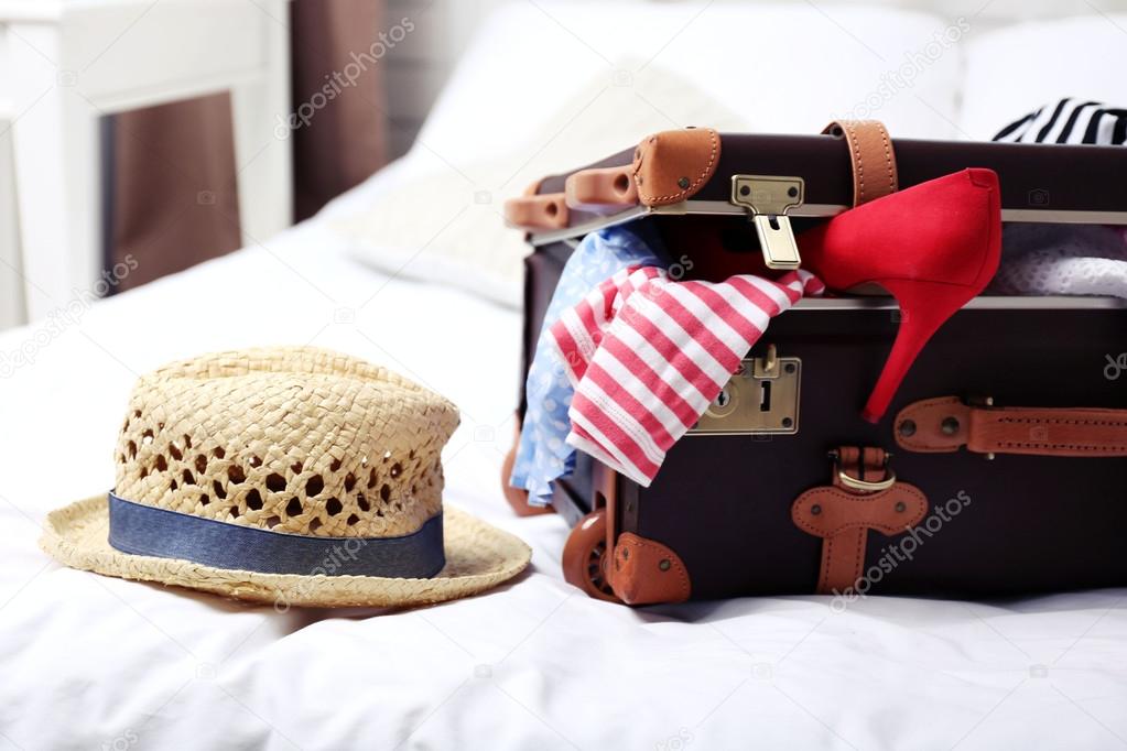 Suitcase with clothing on bed