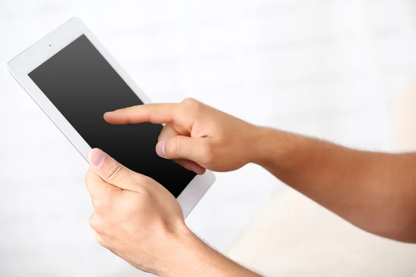 Mano masculina sosteniendo PC tableta en el fondo interior del hogar — Foto de Stock