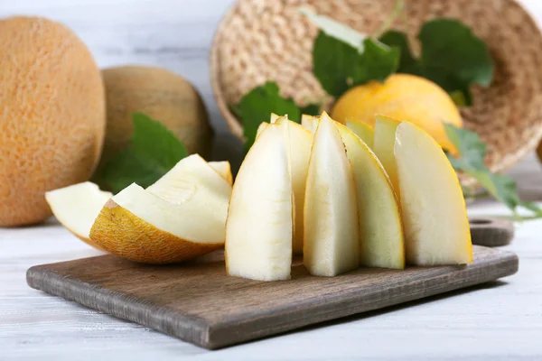 Slices of ripe melons with green leaves on table close up — Stock Photo, Image