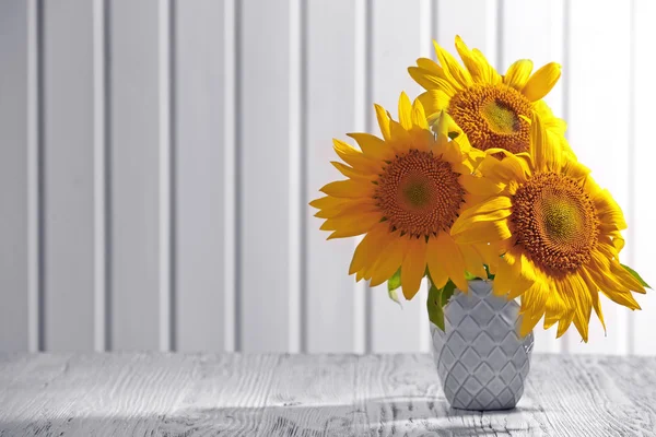 Mooie lichte zonnebloemen in vaas op houten achtergrond — Stockfoto