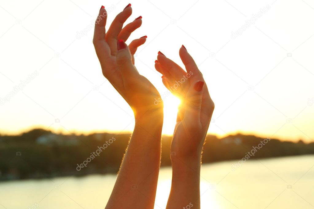 Female hands on sunny sky 