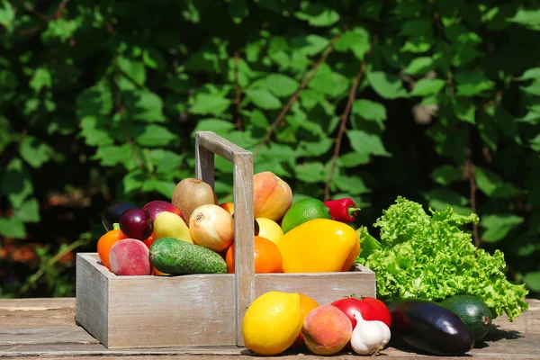 Montón de frutas y verduras frescas en caja en la mesa al aire libre — Foto de Stock