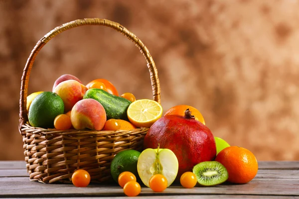 Heap of fresh fruits and vegetables in basket on wooden table close up