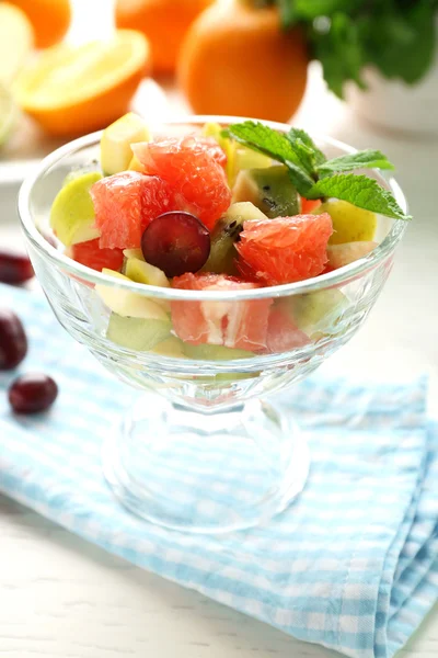 Fruit salad in glass bowl, on light wooden background — Stock Photo, Image