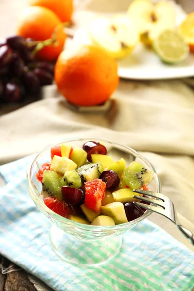 Fruit salad in glass bowl, on wooden background — Stock Photo, Image