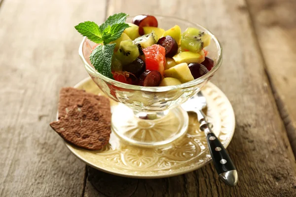 Ensalada de frutas en cuenco de vidrio, sobre fondo de madera — Foto de Stock