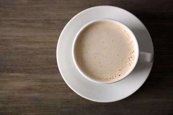 Tasse de café avec mousse sur table en bois, vue sur le dessus — Photo