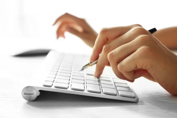 Mano femenina con pluma tecleando en el teclado en la mesa, primer plano —  Fotos de Stock