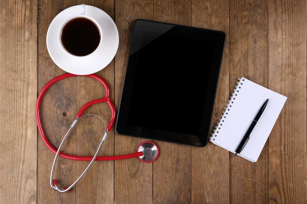 Local de trabalho médico com tablet e estetoscópio em branco sobre fundo de madeira — Fotografia de Stock