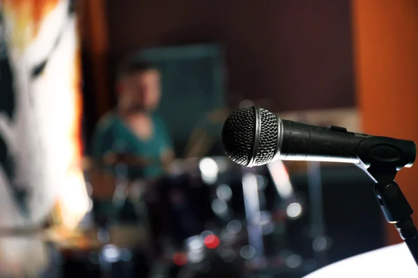 Микрофон, крупным планом, на размытом фоне барабанщика — стоковое фото