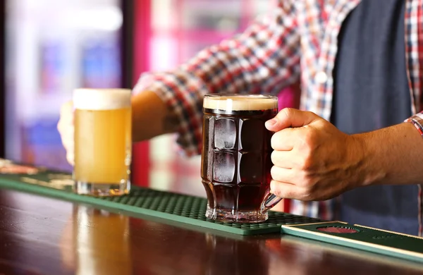 Cantinero sosteniendo vaso de cerveza en el lugar de trabajo — Foto de Stock