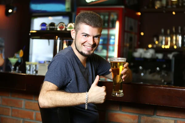 Young man drinking beer in bar — Stock Photo, Image