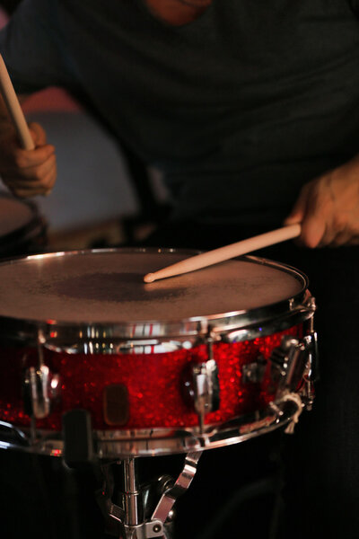 Drummer with wooden sticks and drums on dark background