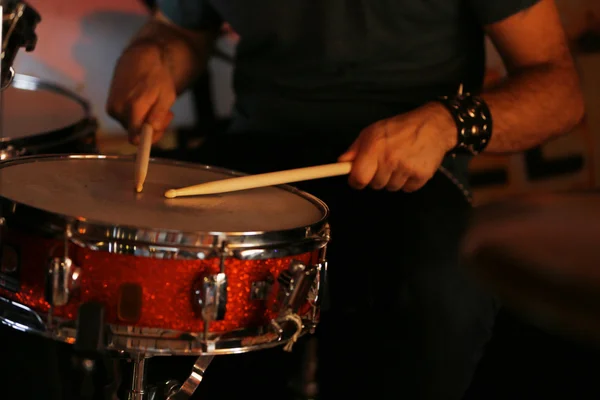 Baterista com bastões de madeira e tambores em fundo escuro — Fotografia de Stock