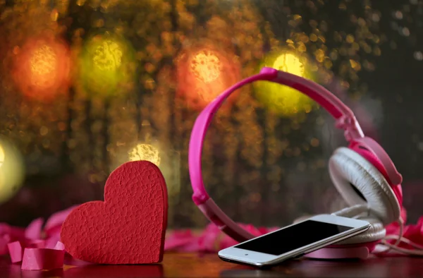 ヘッドフォンと携帯電話のライトの背景に装飾的な心 — ストック写真
