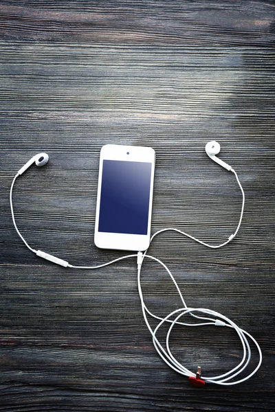 Telefone celular e fones de ouvido com coração vermelho no fundo de madeira — Fotografia de Stock