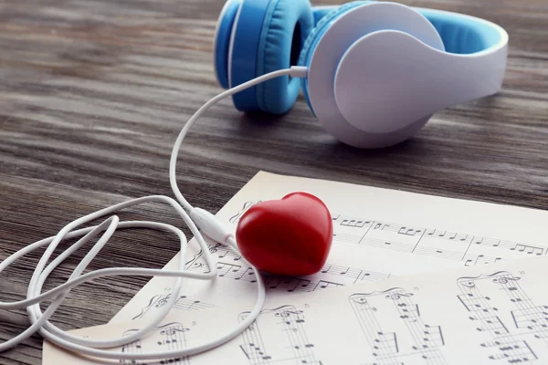 Écouteurs avec coeur rouge et notes de musique sur table en bois close up — Photo