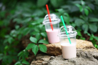 Milkshake açık havada yeşil zemin üzerine plastik bardak