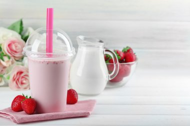 Milkshake hafif ahşap arka plan üzerinde plastik bardak