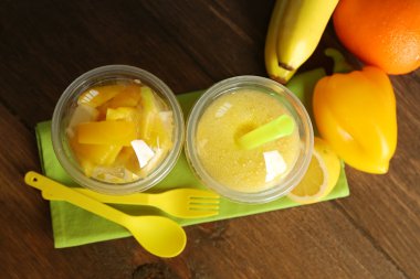 sebze ve meyve salatası ve sağlıklı taze ahşap arka plan üzerinde plastik bardak içki. Renkli diyet kavramı