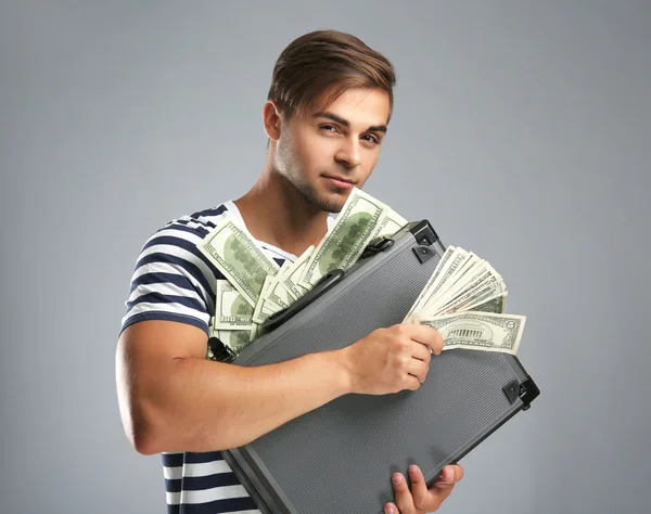 Красивий молодий чоловік тримає справу з грошима на сірому фоні — стокове фото