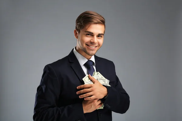 Елегантний чоловік у костюмі тримає гроші на сірому фоні — стокове фото