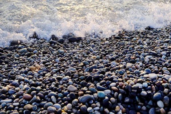 Donkere natte keien strand met zee golven — Stockfoto