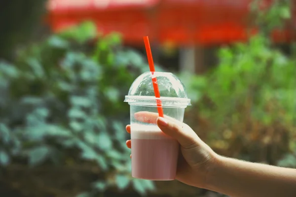 Femme tenant tasse en plastique de milkshake gros plan, à l'extérieur — Photo