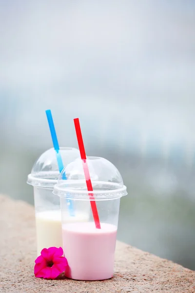 Copos de plástico de milkshake no fundo claro, ao ar livre — Fotografia de Stock